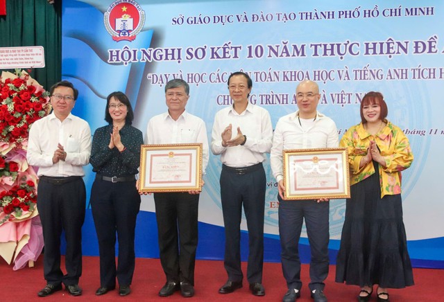 Ông Phạm Ngọc Thưởng, Thứ trưởng Bộ Giáo dục và Đào tạo (thứ ba từ phải qua) và bà Trần Thị Diệu Thuý (thứ hai từ trái qua) trao bằng khen cho Sở Giáo dục và Đào tạo TPHCM và EMG Education