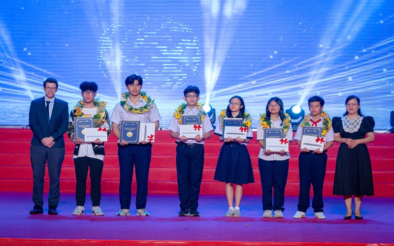 Đại diện EMG Education và bà Đinh Việt Nga - Chuyên viên Văn phòng UBND TP.HCM - trao thưởng cho các học sinh